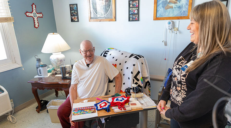 Jeanny Camden, LPN, stops by to see resident John Thomas’ latest crafty creations at the Good Samaritan Society - Villisca in Iowa.