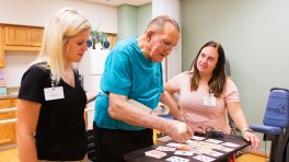 Occupational therapy assistant Sara Luenberger (right) and physical therapy assistant Bridgette Jackson support Jim Schoenrock during a balance exercise.