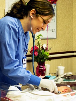 Nurse uses her stethoscope to check the heart beat of a newborn infant. 