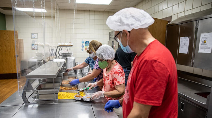 Volunteers wearing masks and gloves while serving food